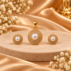 Gold jewelry set featuring a round pendant and two matching stud earrings, each with a white pearl surrounded by a halo of small clear stones, displayed on a beige stone slab with gold satin fabric and white flowers.
